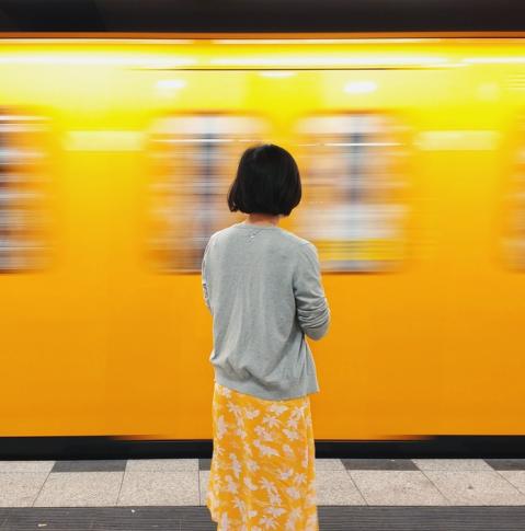 Frau schaut auf eine fahrende Berliner U-Bahn