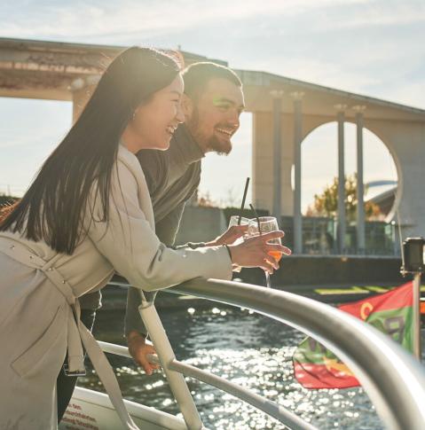 Mann und Frau genießen einen Cocktail bei einer Schiffsrundfahrt in Berlin