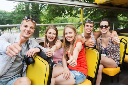 friends traveling by tour bus showing thumbs up