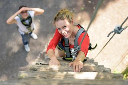 Waldhochseilgarten Jungfernheide Junge Frau klettert eine Holzleiter empor